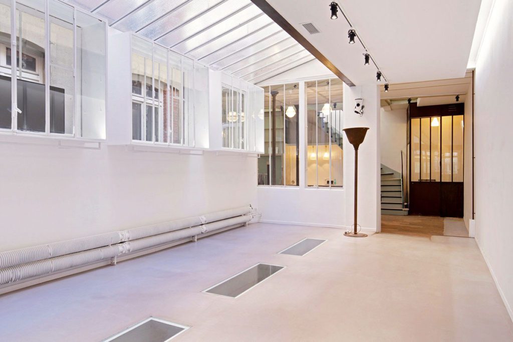 Glass-roof Marais showroom, stone wall and vents, 118 Rue de Turenne Paris