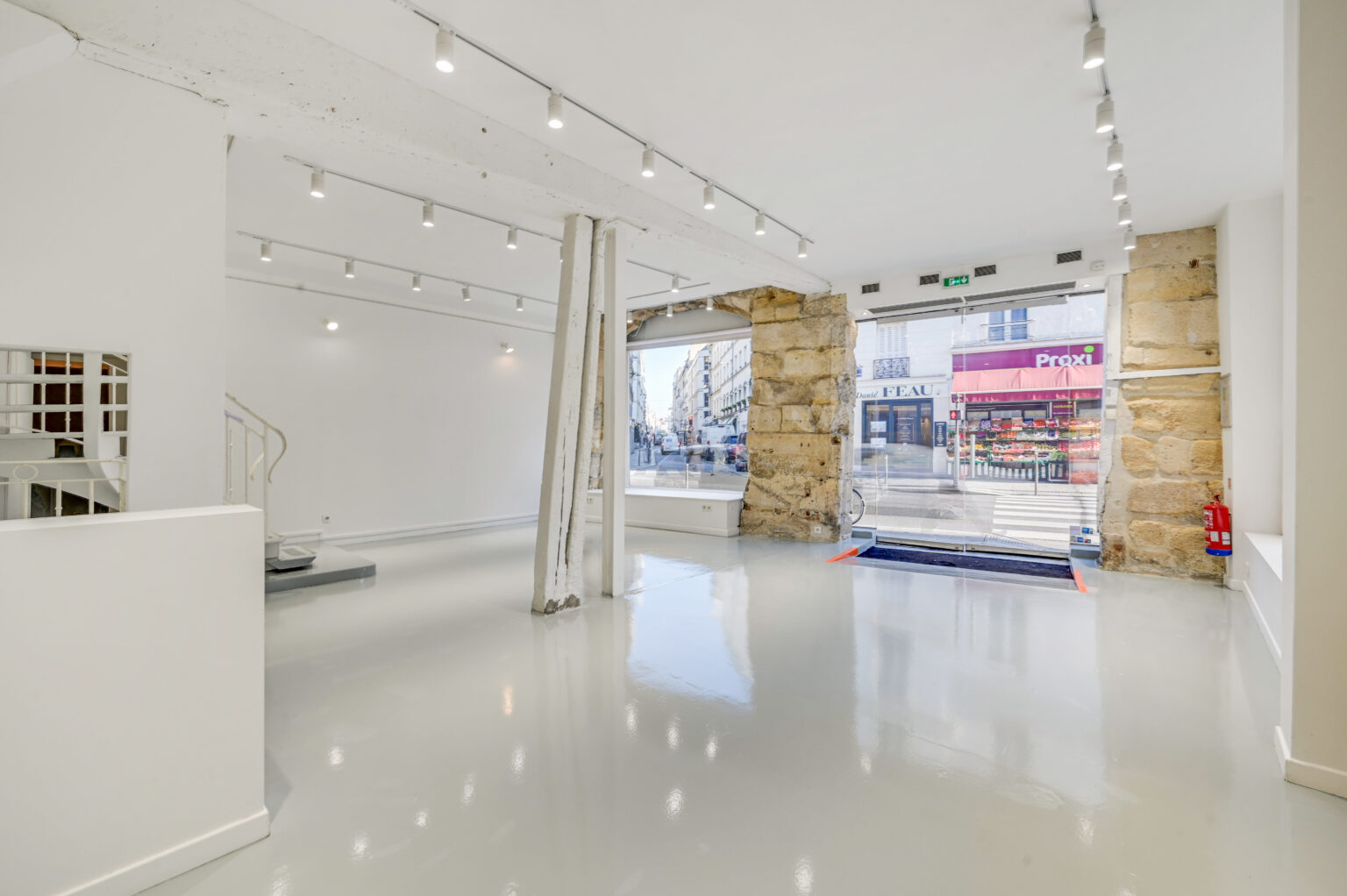 Ground floor showroom with resin floor, track lighting, and corner windows at 97 Rue de Turenne, Paris
