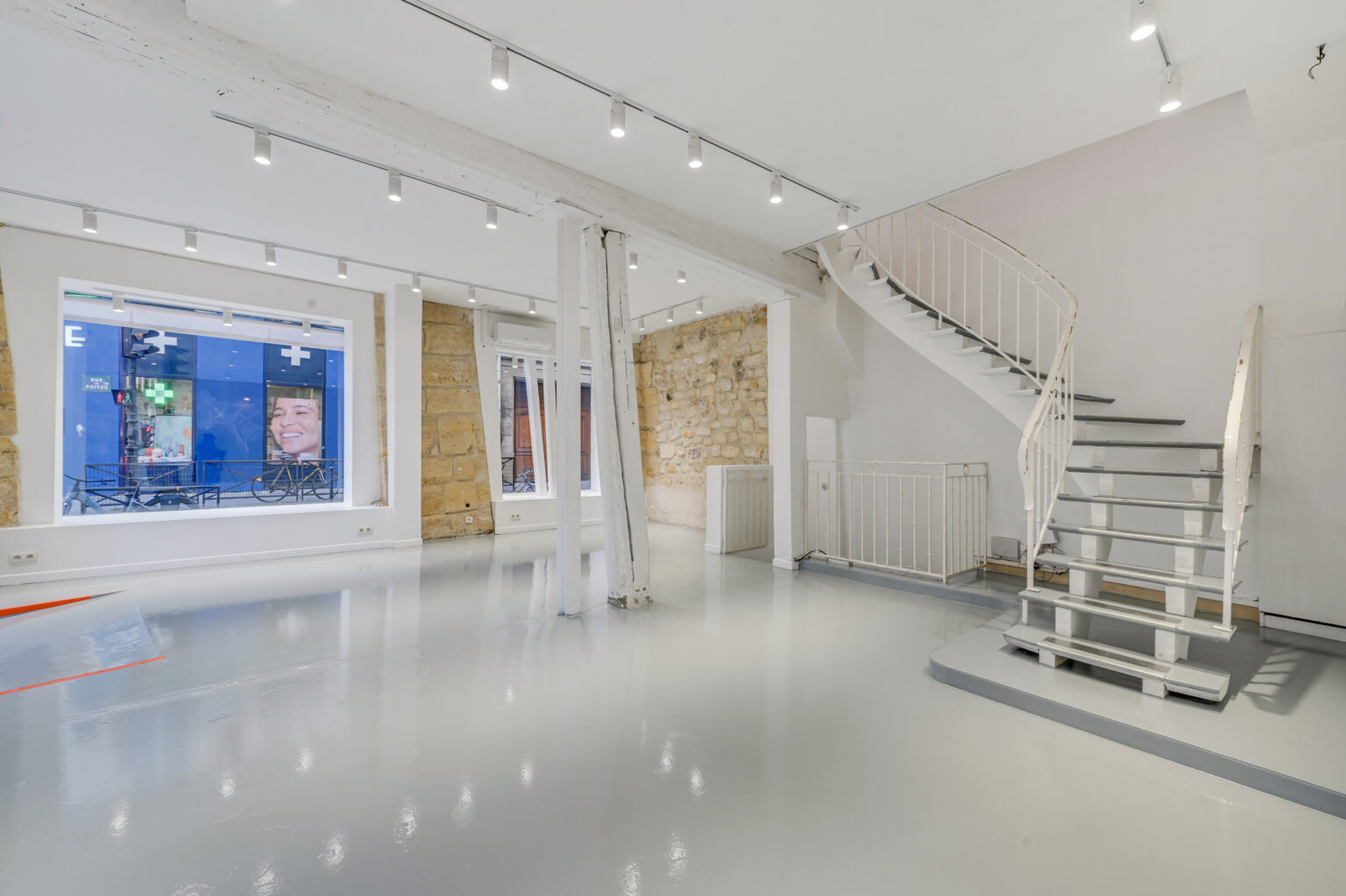 Ground floor showroom with staircase and exposed stone details at 97 Rue de Turenne, Paris