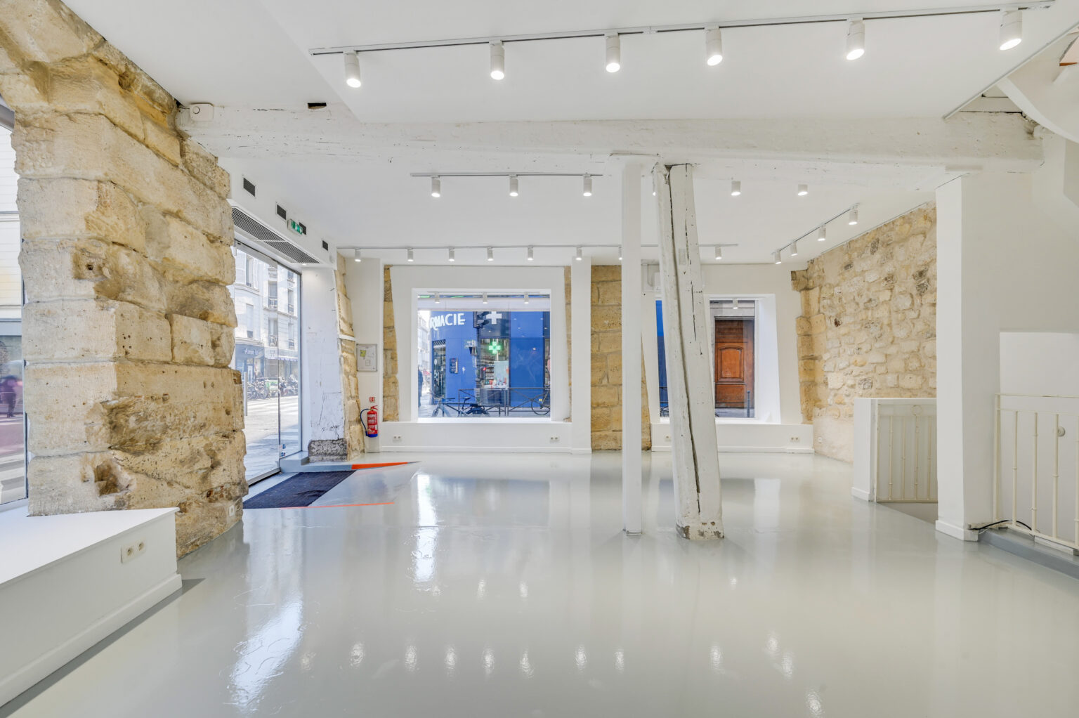 Wide ground floor showroom with exposed stone wall and track lighting at 97 Rue de Turenne, Le Marais