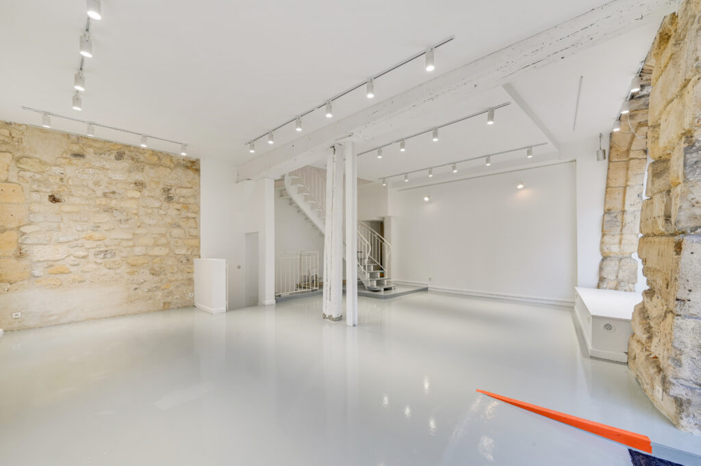 Open plan ground floor showroom with street-facing windows at 97 Rue de Turenne, Paris