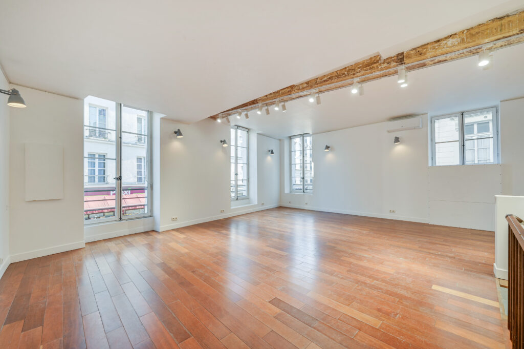 First floor showroom with wood floors, exposed beam, and large windows at 97 Rue de Turenne, Paris
