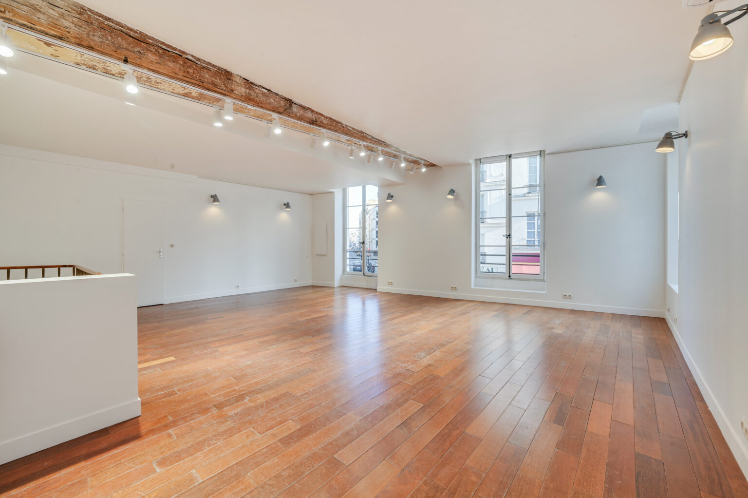 First floor showroom wide view with exposed beam lighting and wood floor at 97 Rue de Turenne, Paris