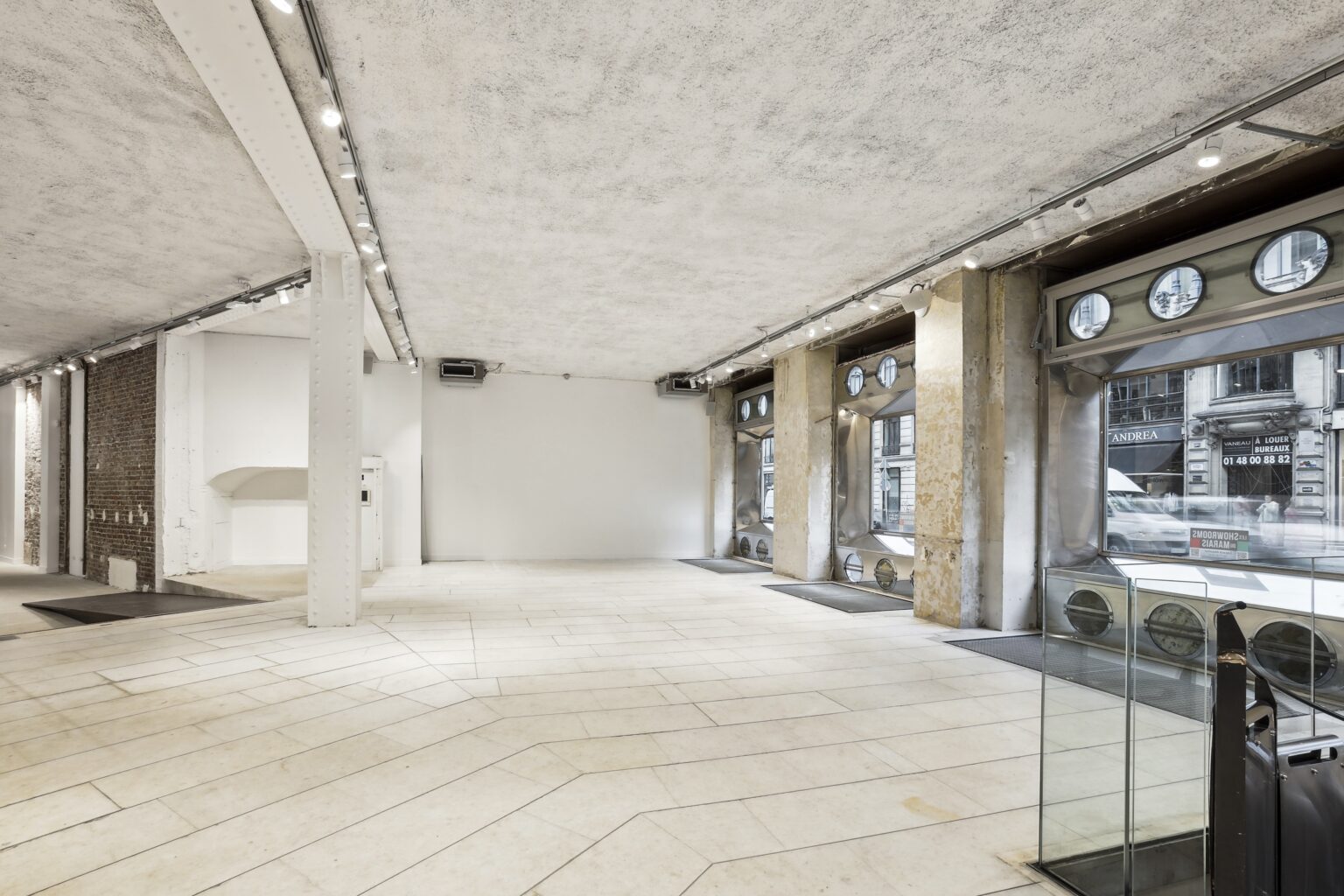 Wide ground-floor view at Espace Reaumur with open-plan layout, track lighting, and street-facing windows