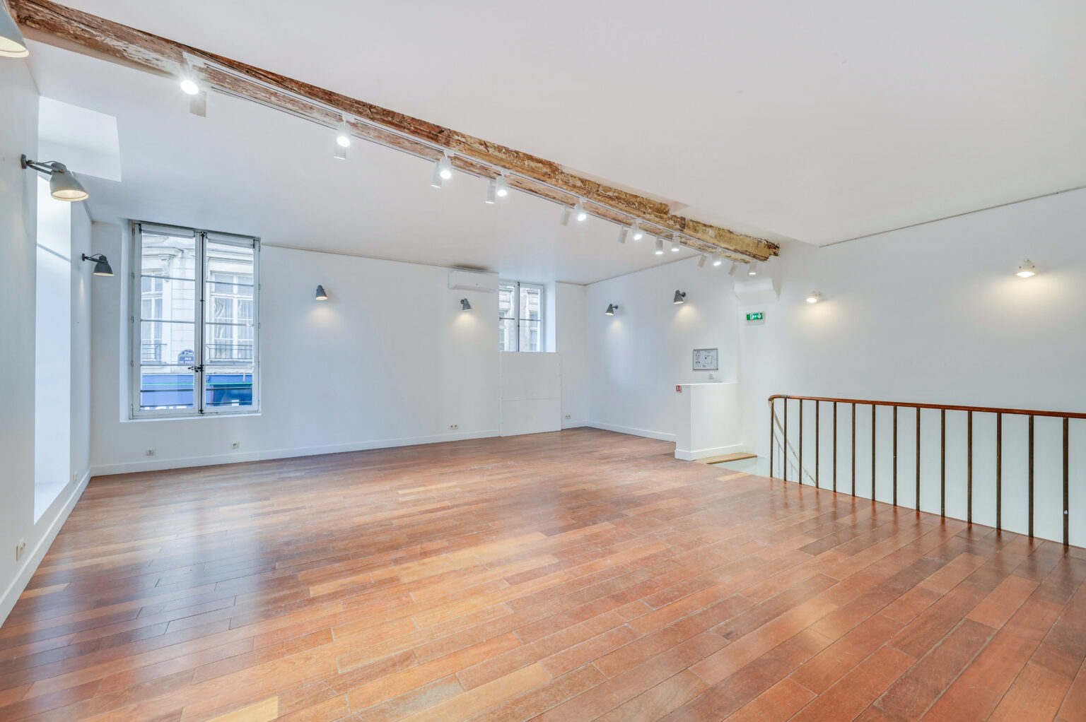First floor showroom with railing overlooking staircase and wood floors at 97 Rue de Turenne, Paris