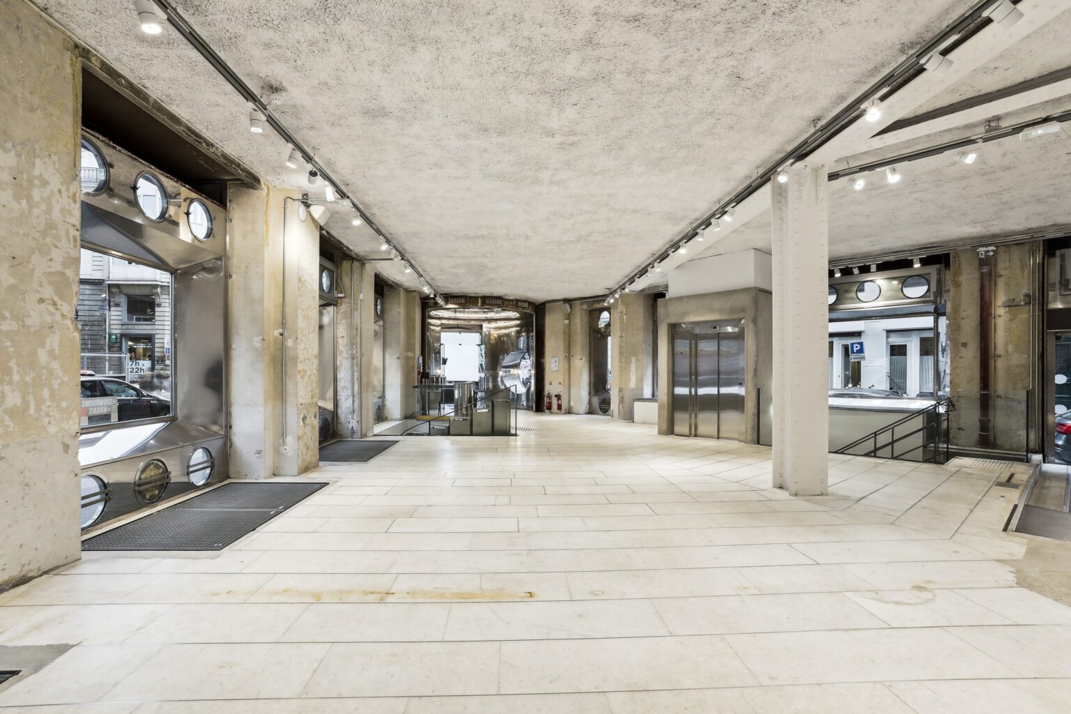 Long interior perspective at Espace Reaumur showing the main circulation axis, elevator core, and frontage windows