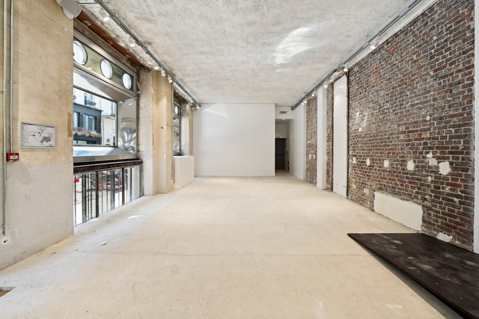 Side passage inside Espace Reaumur with exposed brick, gallery lighting, and window light