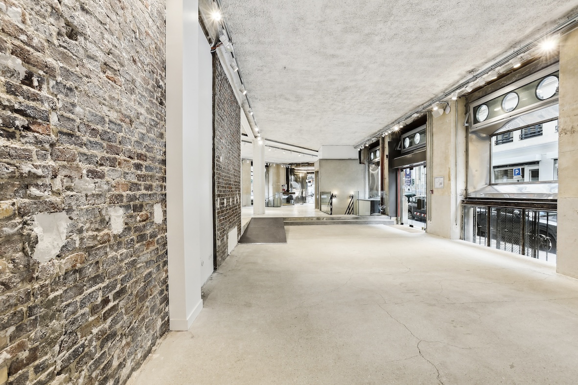 Display zone at Espace Reaumur with exposed brick wall, level change, and open merchandising area