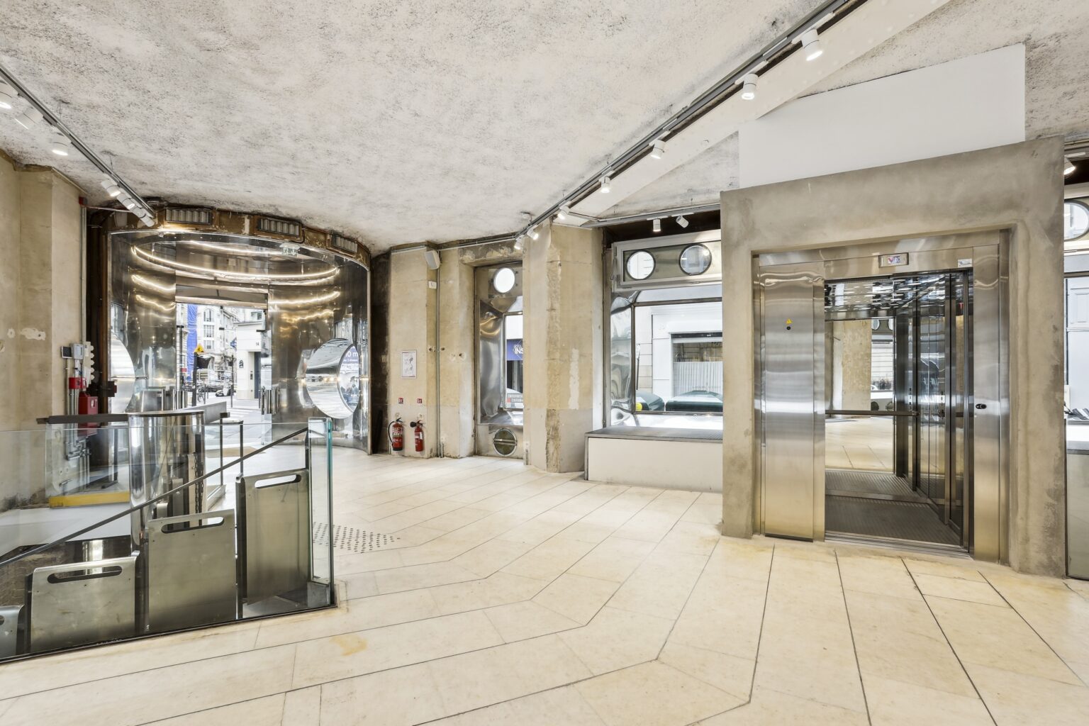 Entrance lobby with stainless steel portal, elevator doors, display windows and glass balustrade around the stair opening.