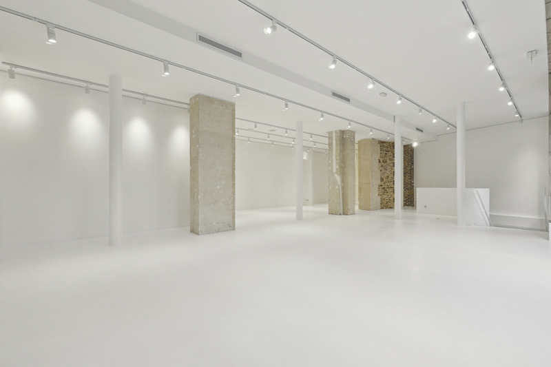 Interior view showing multiple columns, track lighting, and an open white floor.