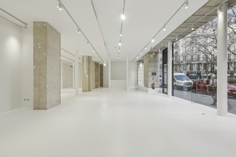 Bright interior facing the glass storefront, with columns and street traffic visible outside.