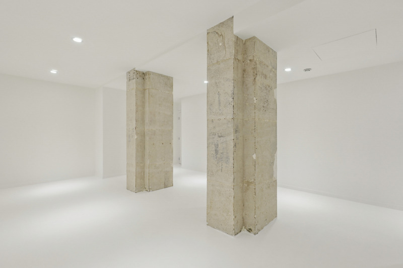 Close interior view of two large raw stone columns in a white room.