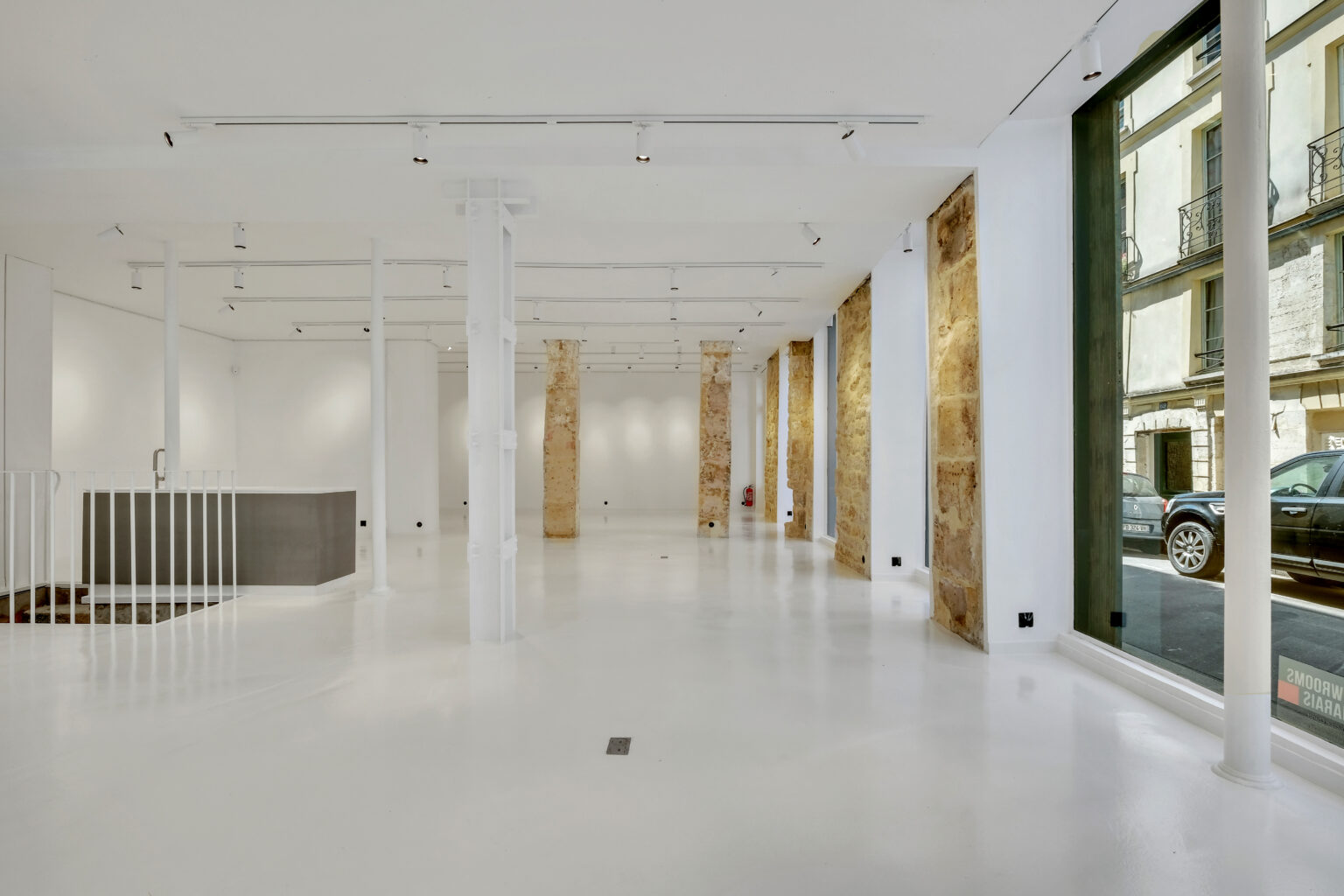 Main interior space with white floors and stone columns, 62 Rue Charlot