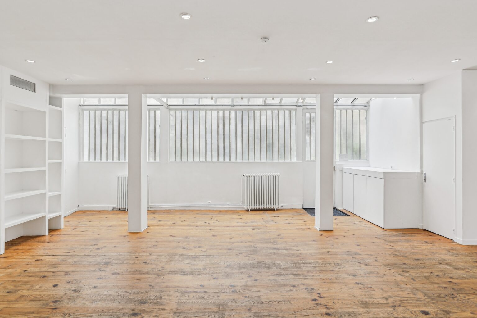 Wide ground floor showroom space with pillars and wooden flooring.
