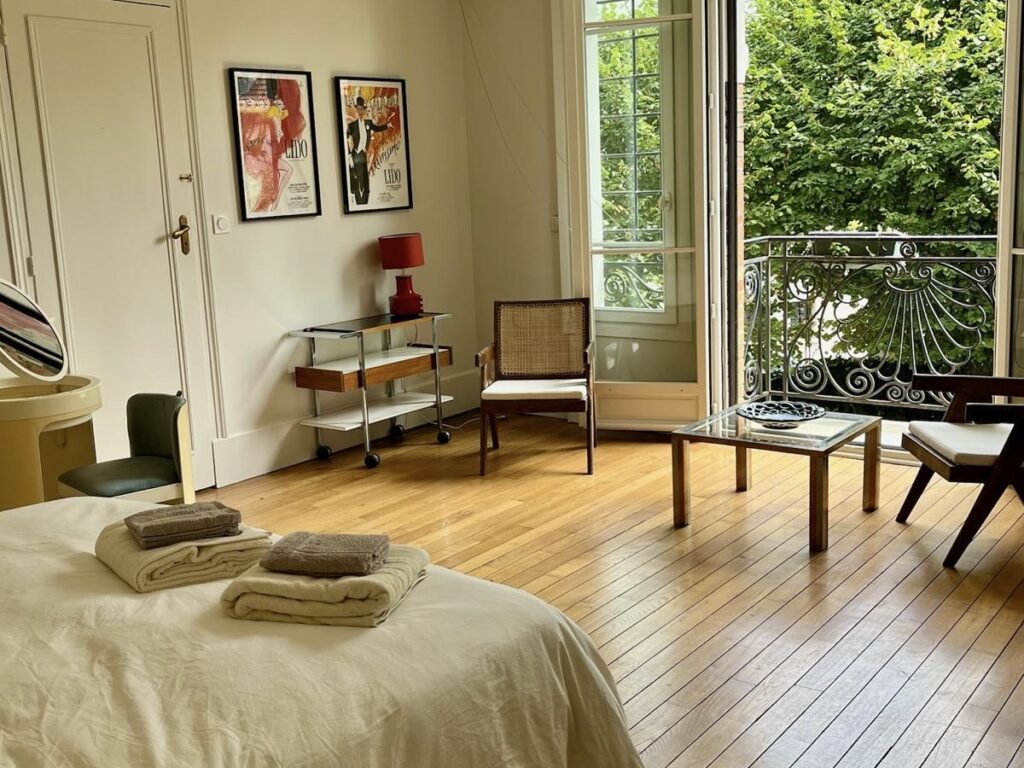 Bedroom at Villa Paul Strauss with desk, chairs, wood floor and open view onto the garden.