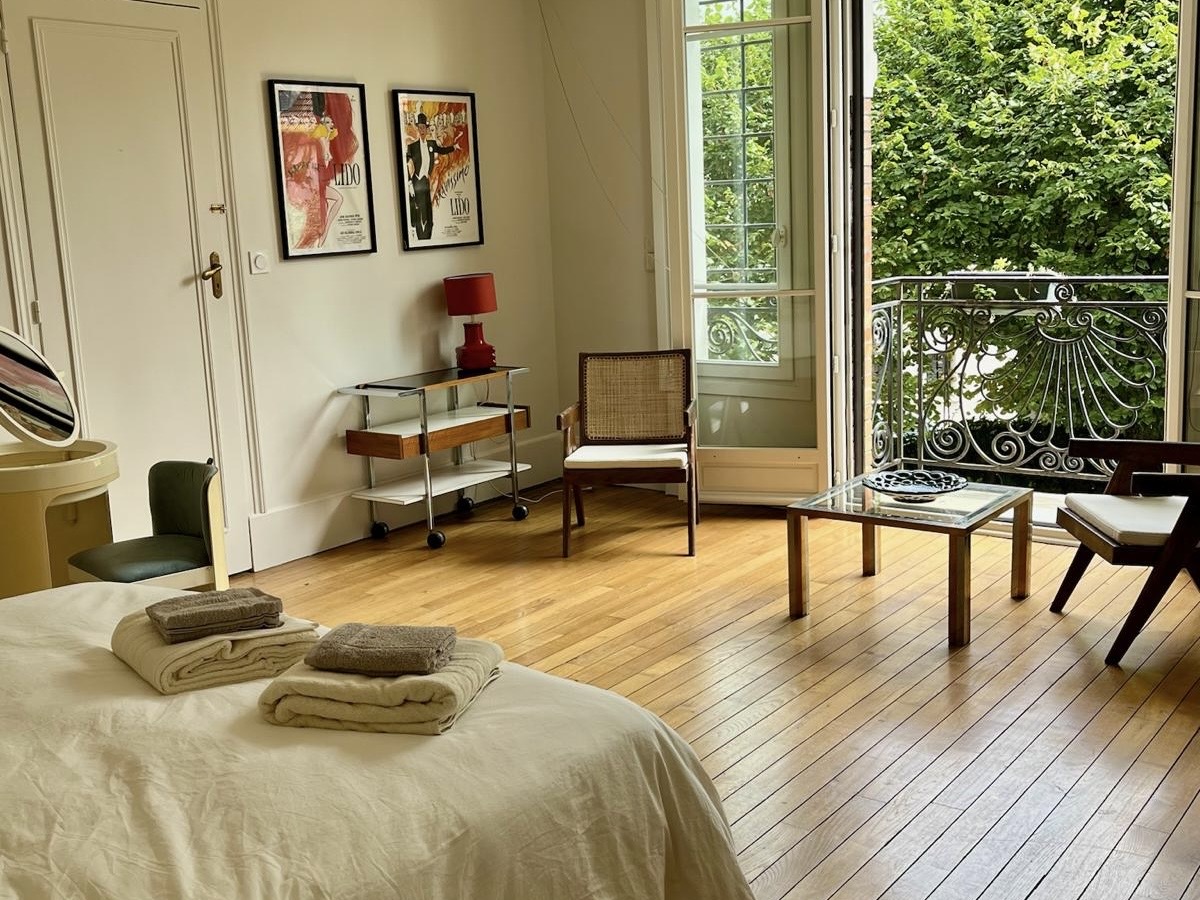 Bedroom at Villa Paul Strauss with desk, chairs, wood floor and open view onto the garden.