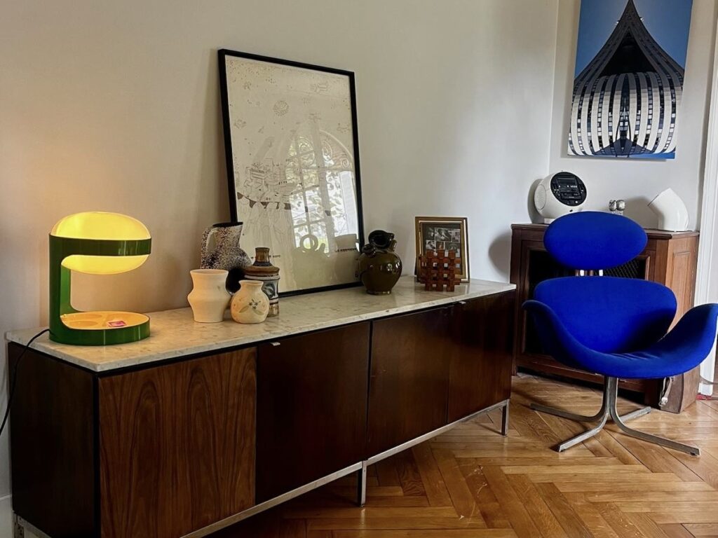 Bedroom interior at Villa Paul Strauss with wooden desk, mirror, table lamp and blue chair.