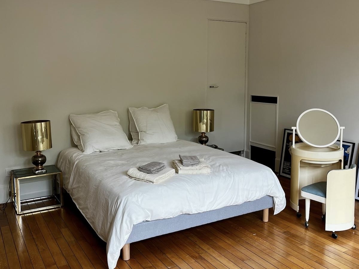 Bedroom at Villa Paul Strauss with double bed, vanity table, wardrobe and wood parquet floor.
