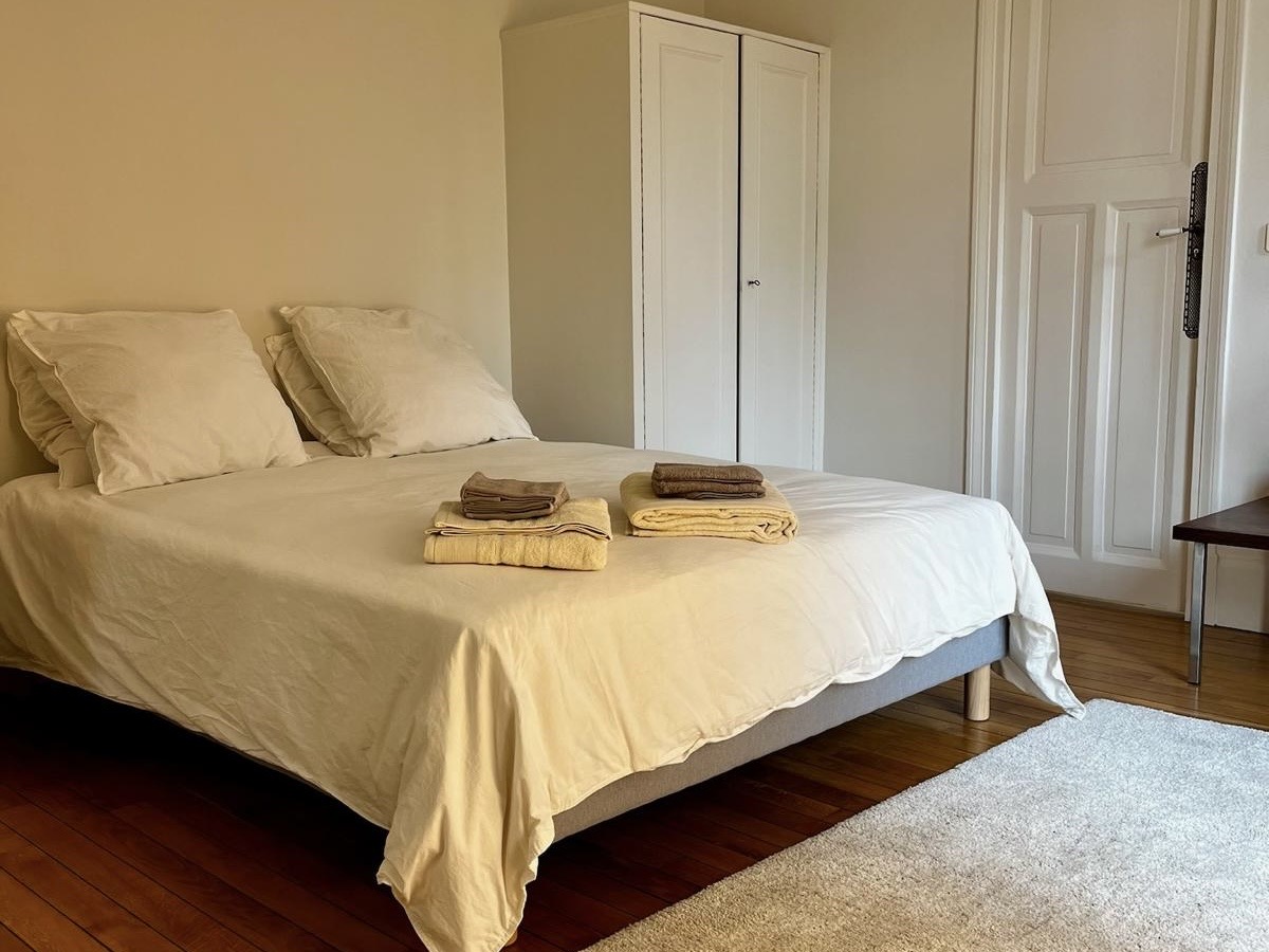 Bedroom at Villa Paul Strauss with double bed, built-in wardrobe and warm wood flooring.
