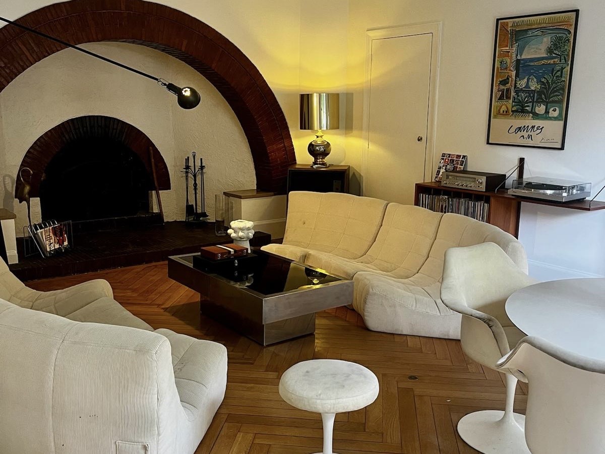 Lounge at Villa Paul Strauss with curved fireplace, sofas, coffee table and warm lighting.