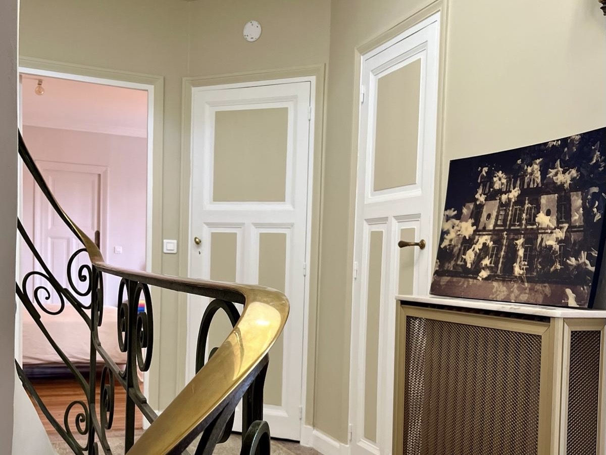 Staircase landing at Villa Paul Strauss with banister, wall mouldings and framed artwork.