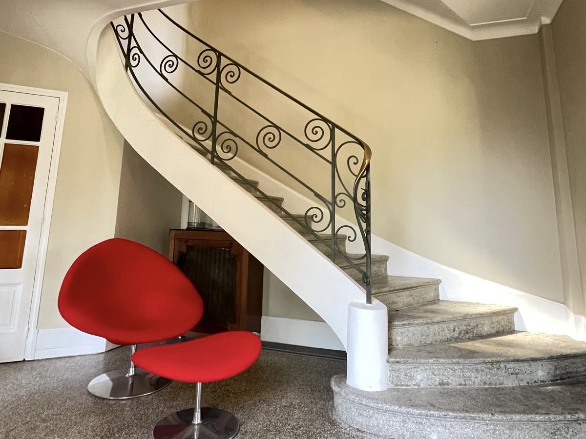 Statement staircase with red chair and sculptural lines.