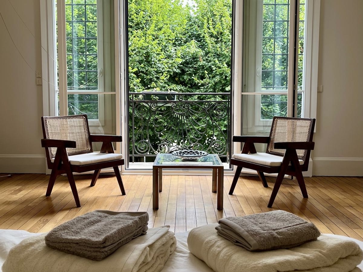 Window seating area at Villa Paul Strauss with chairs, floor cushions and garden-facing windows.