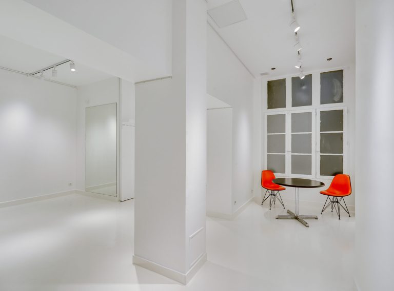 Open-plan main room, white walls and gallery lighting — 43 Rue Charlot