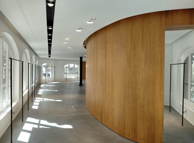 Curved wood pod along a glazed aisle on the first floor