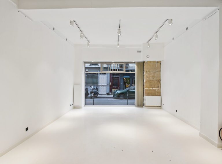 White-box interior with gallery track lighting and window to Rue Charlot — 52 Rue Charlot showroom