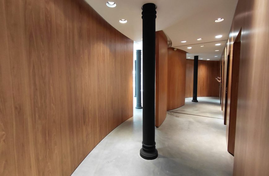 Curved wood corridor with cast-iron column, bright upper level