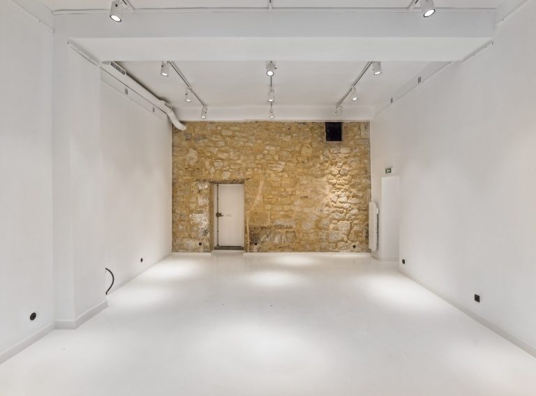 Rear room with historic stone wall — 52 Rue Charlot showroom, Marais Paris