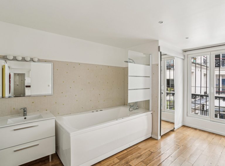 White tiled secondary bathroom with tub in loft studio, Marais showroom