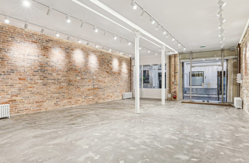 Long gallery perspective with stone wall and spot lighting — Paris 2 venue