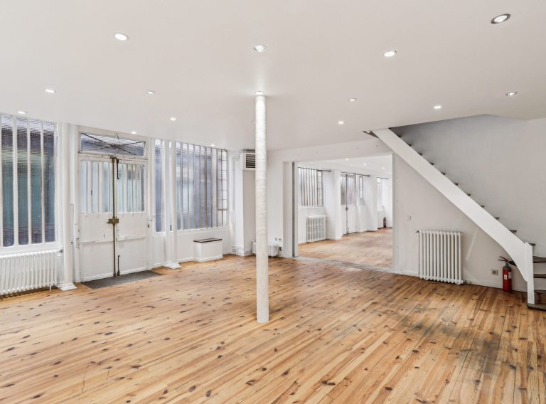 Wide showroom shot with central column, lounge corner and skylight, Marais