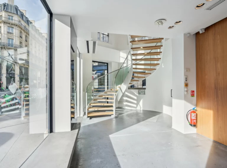 Street-level entrance with glass façade, bright interior and stair in the background.