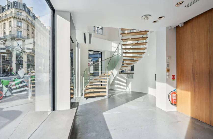 Street-level entrance with glass façade, bright interior and stair in the background.