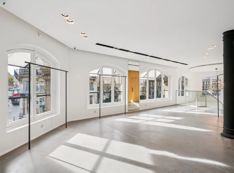 Bright first-floor room with arched windows, black column and wood volume.