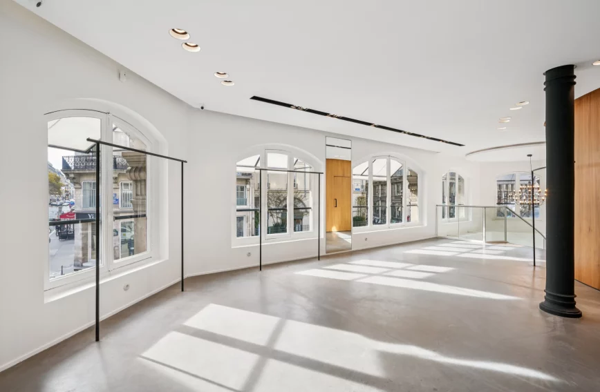 Bright first-floor room with arched windows, black column and wood volume.