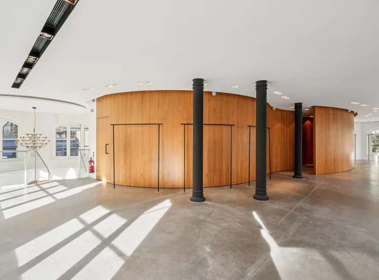 Upper floor with curved wood pod and series of black structural columns.