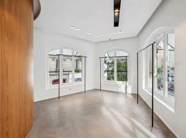 Corner first-floor room with arched street windows and polished concrete floor.