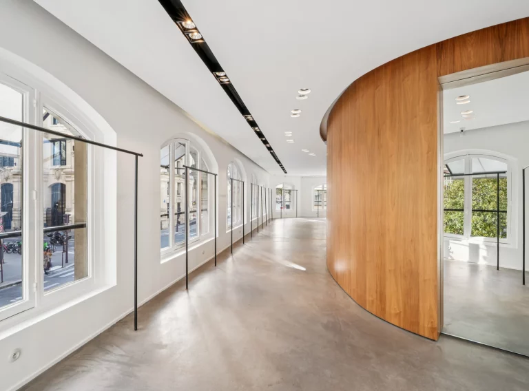 Curved wood wall facing a long run of windows in the first-floor gallery.