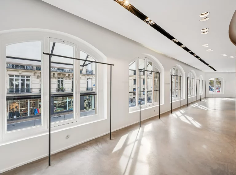 Arched windows with integrated hanging rails along a bright first-floor façade.