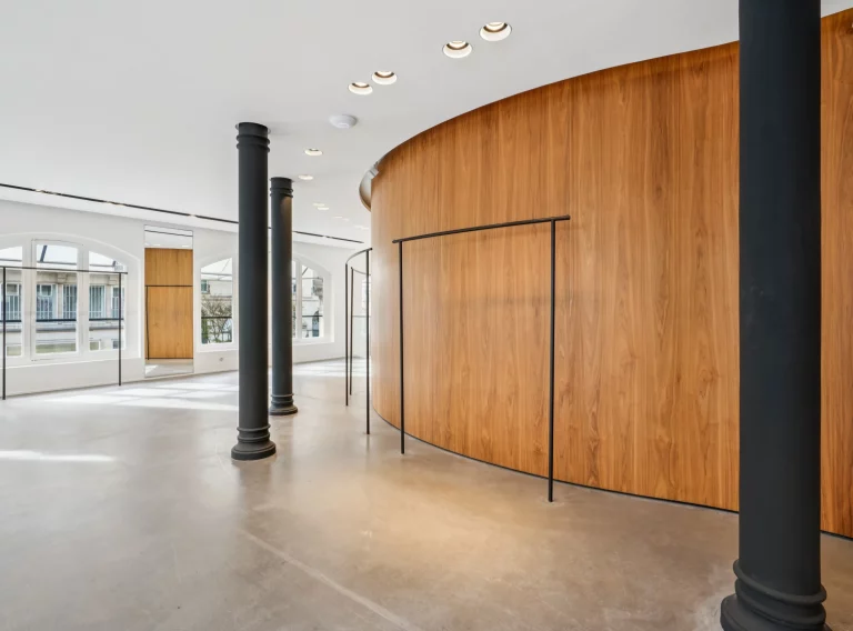 Black column, curved wood pod and open concrete floor on the upper level.