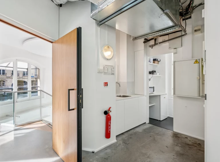 Back-of-house technical room with exposed ceiling, storage and fire safety equipment.