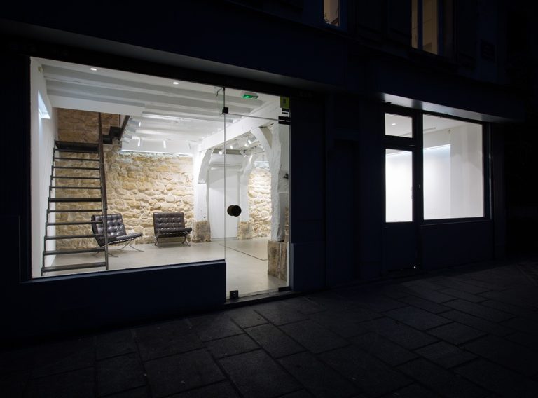 Night view through showroom windows — Rue de la Corderie, Paris 3